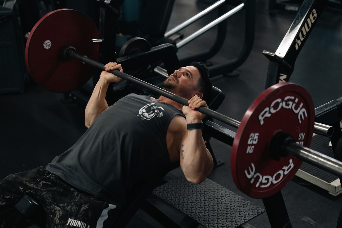 Man lifting barbell on incline bench for upper chest workout.